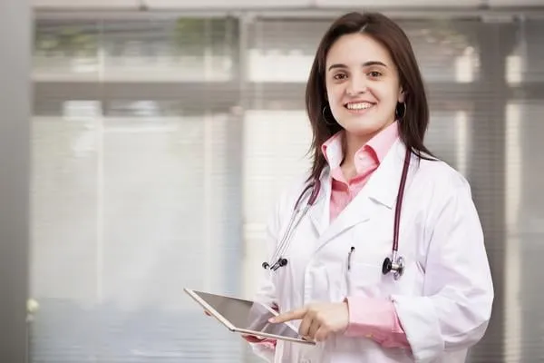 souriant femme médecin debout avec une tablette pc
