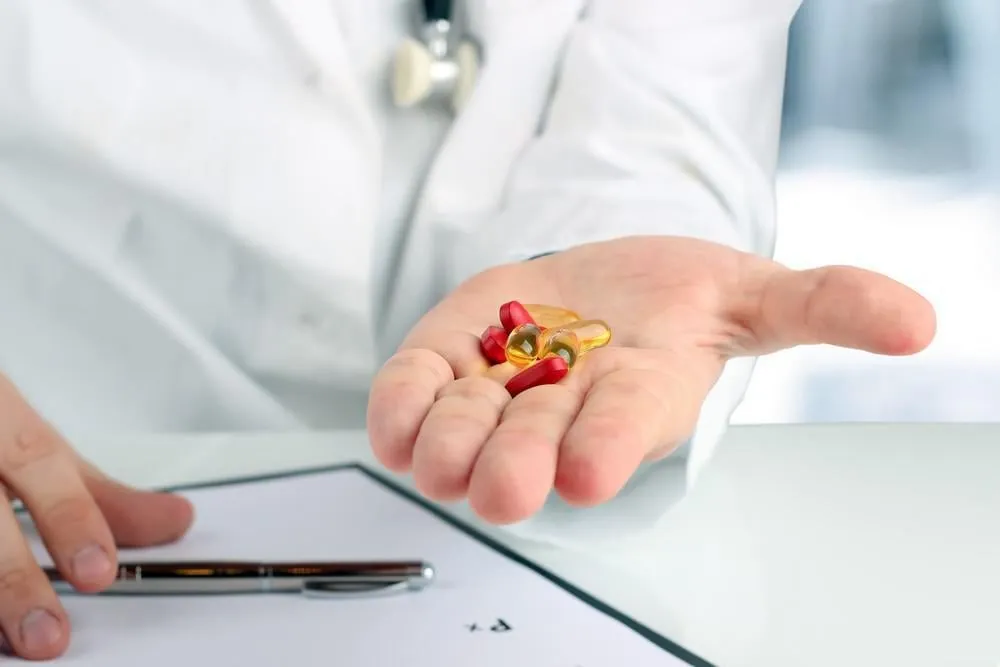 médecin dans une blouse blanche donnant des pilules