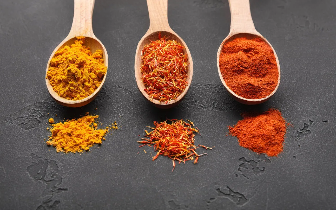 colourful powder spices in spoons on stone table