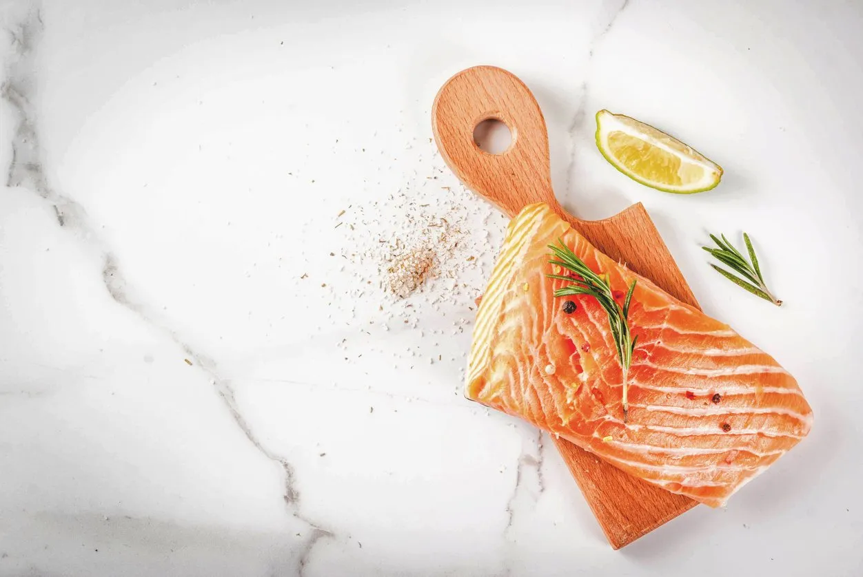 fresh raw fish salmon, steak fillet, with spices, lime, rosemary, salt, on white marble background, copy space top view