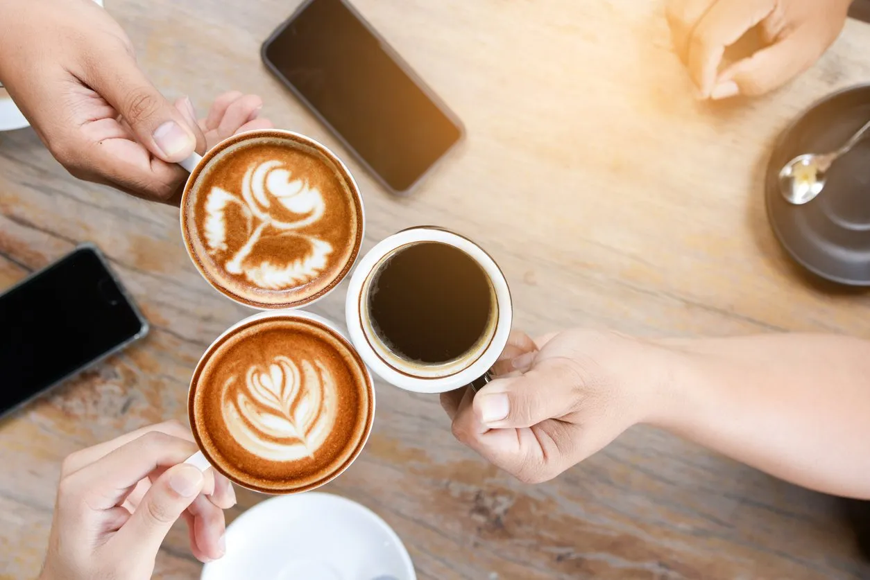 group of people having a meeting after successful business negotiation in a coffee shopdrinking hot beverage latte art coffee
