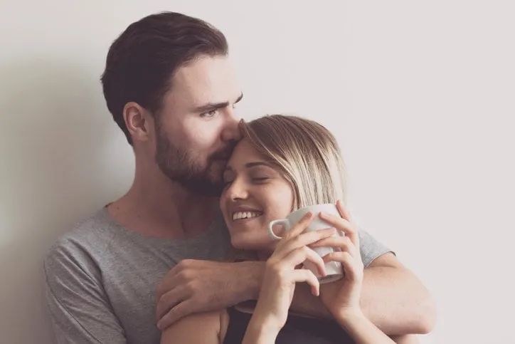 couple in bed young white male and blonde female man kissing woman, happy smile modern couple lifestyle concept