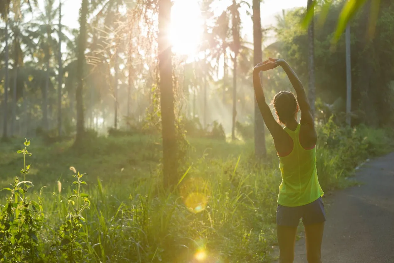 fitness young woman runner warming up before run on morning tropical forest trail