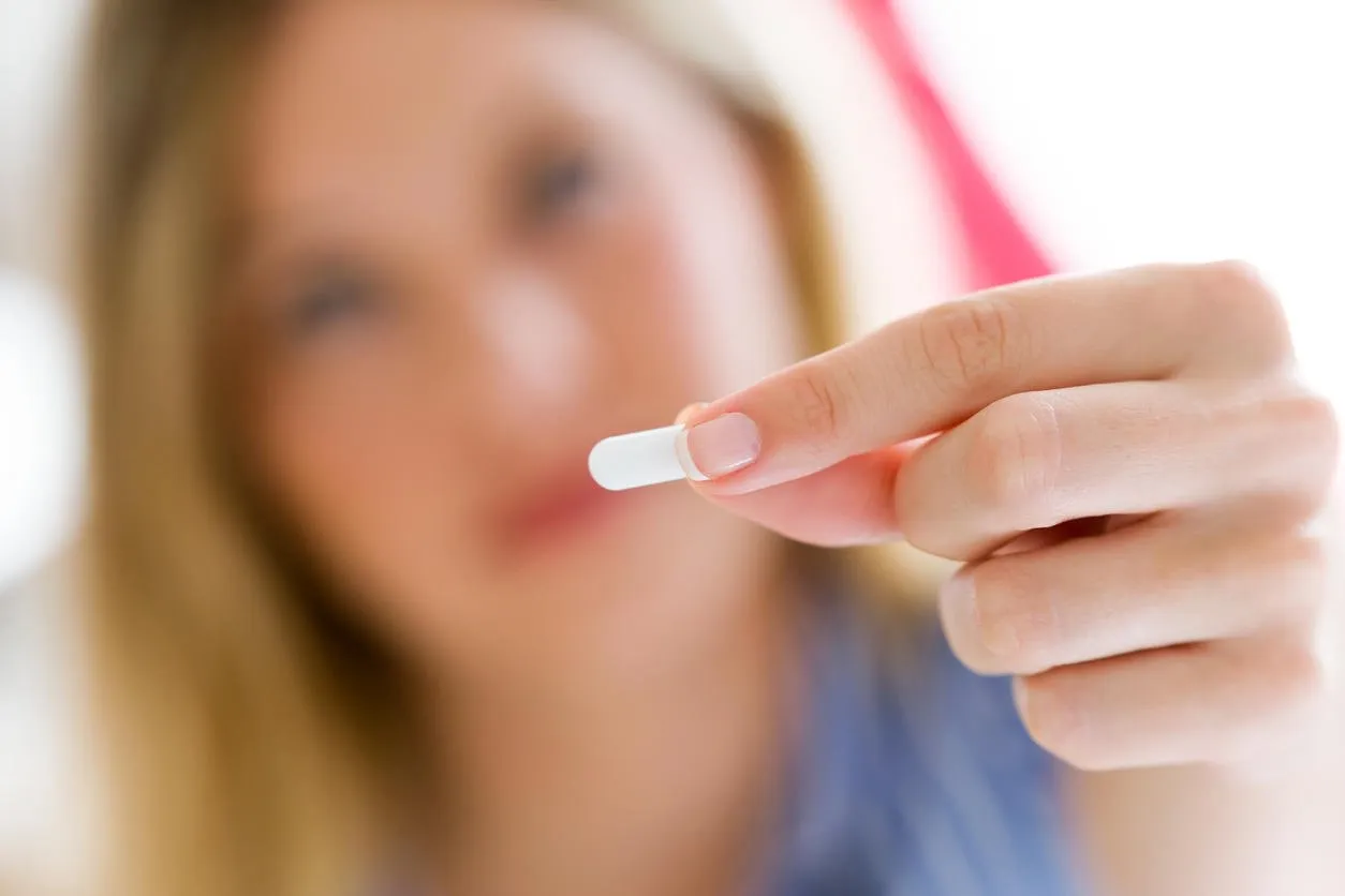 portrait of depressed young woman taking pills at home
