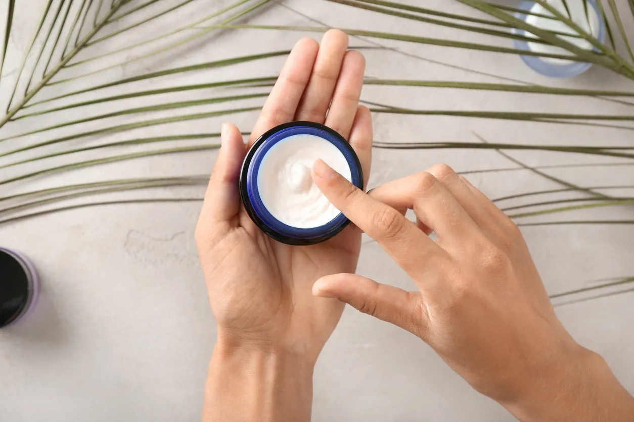 young woman applying body cream, closeup
