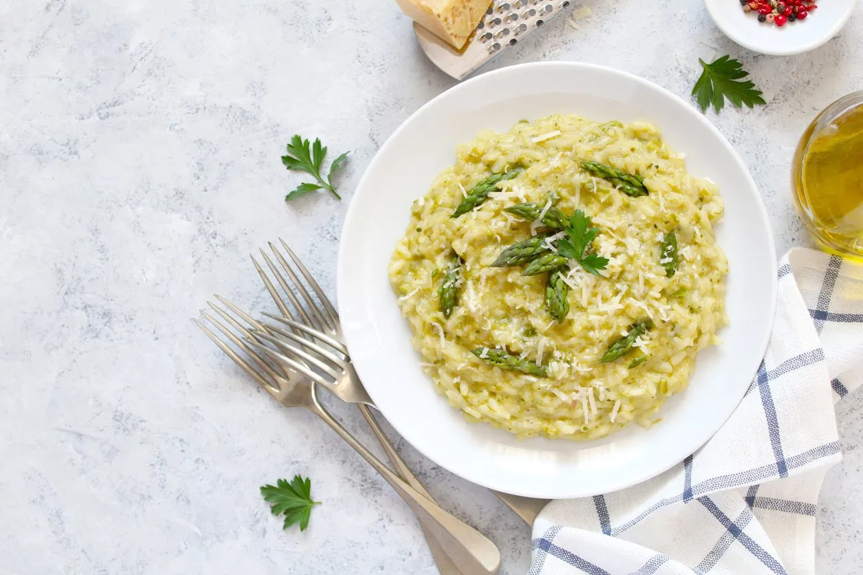 italian risotto with spring asparagus and parmesan cheese in plate on light background