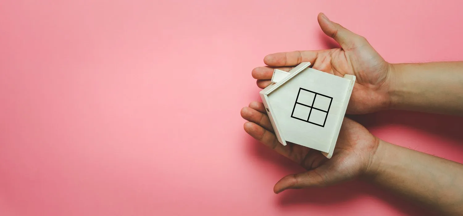 table top view aerial image of hands holding house wooden on blue paper with copy spacesafe stay at home for social distancing of coronavirus (covid-19) or homeless loan concept family international