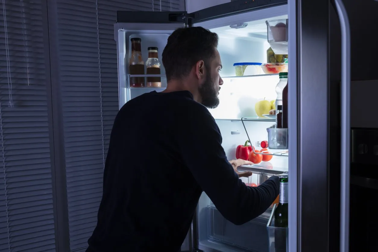 rear view of a young man looking at food kept in refrigerator