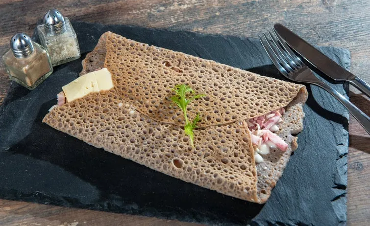 breton crepe with cheese and bacon in a white plate