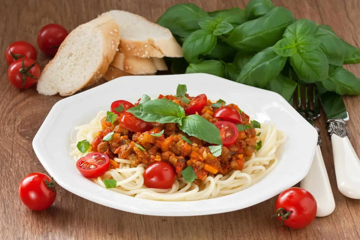 sauce spaghetti bolognaise avec tomate cerise et feuille de basilic sur fond en bois rustique