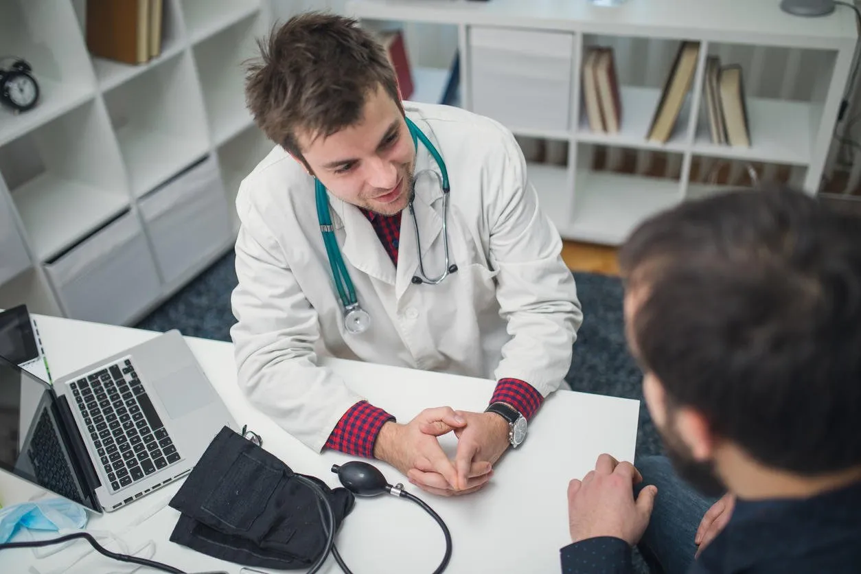 young doctor and his patient talking about patients problems in doctors office