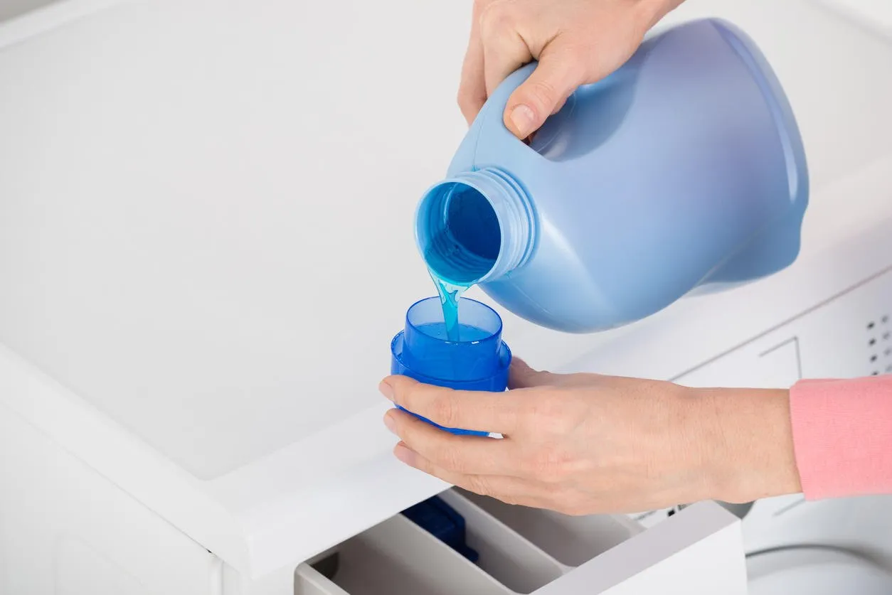 close-up of female hand pouring detergent in the blue bottle cap