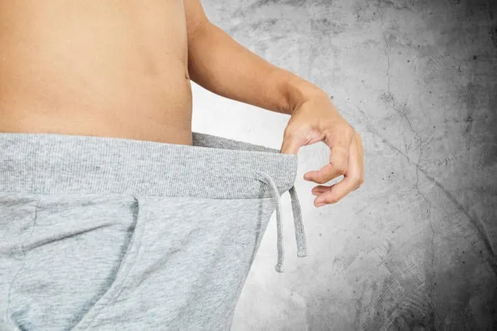 mec asiatique tirant un pantalon chaud, concept abstrait, sur fond de béton