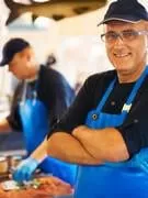 un homme souriant à son magasin de poisson avec ses collègues de travail