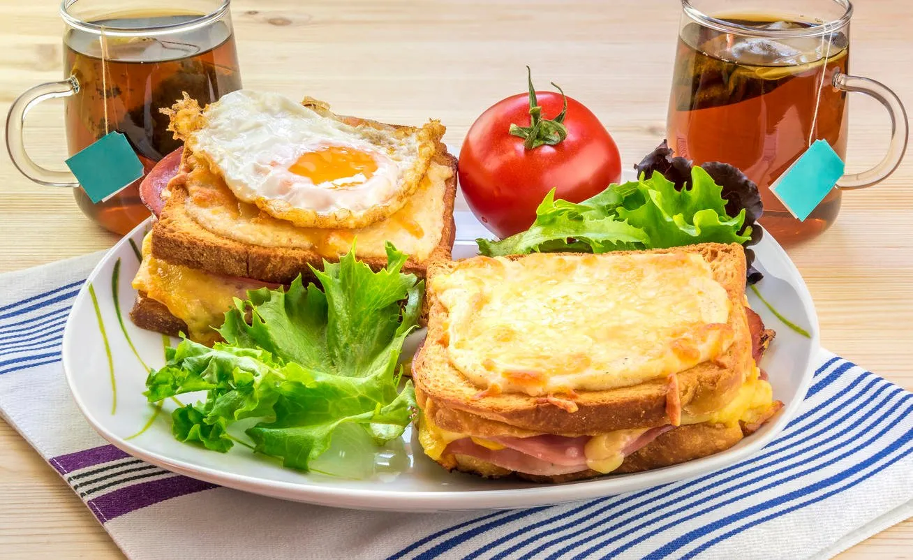 petit déjeuner savoureux pour deux personnes avec une cuisine française spécifique, croque madame (avec œuf) et croque monsieur, assaisonné avec de la salade fraîche et du thé