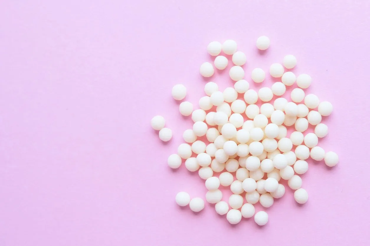 homeopathic globules on pink background alternative homeopathy medicine herbs, healtcare and pills concept flatlay top view copyspace for text