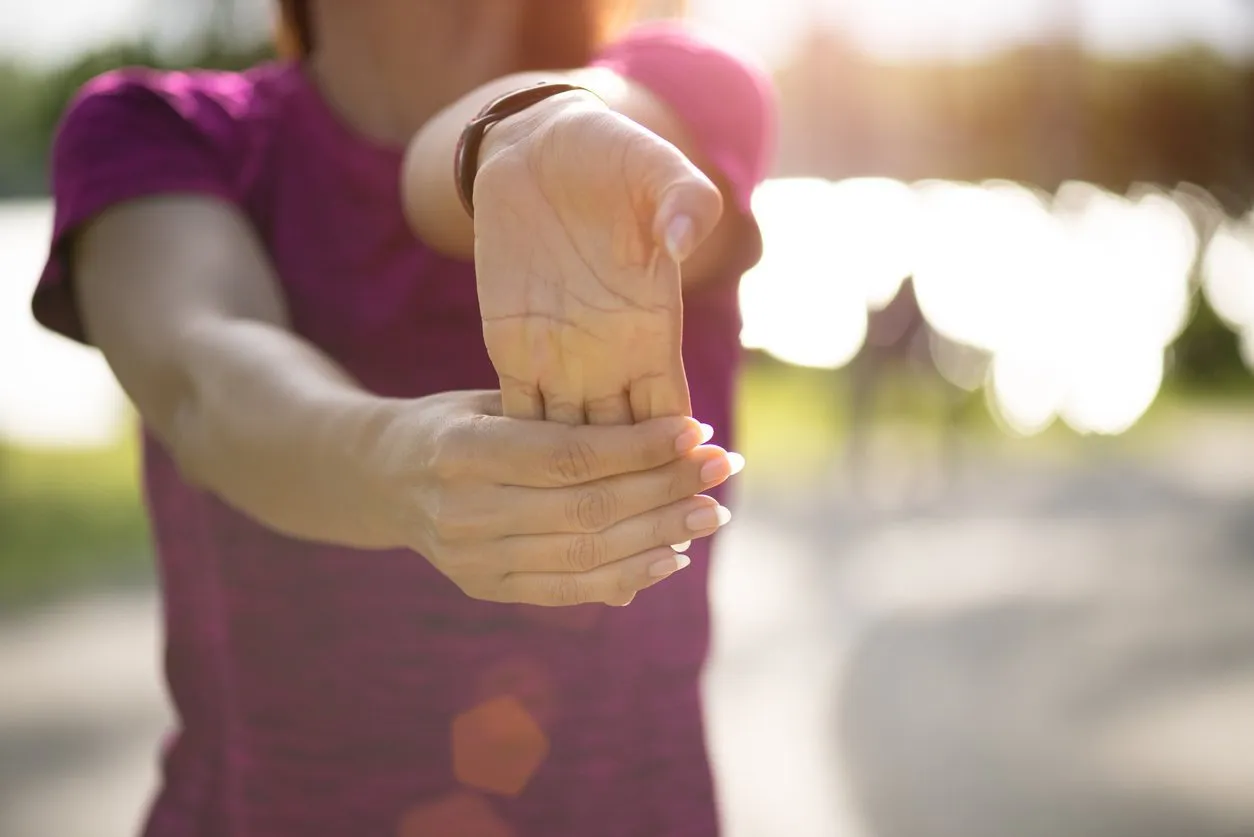 young fitness woman runner stretching hand before run in the park outdoor exercise activities concept