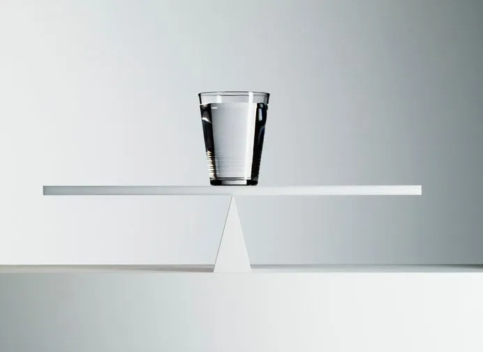 glass of water balancing on middle of seesaw