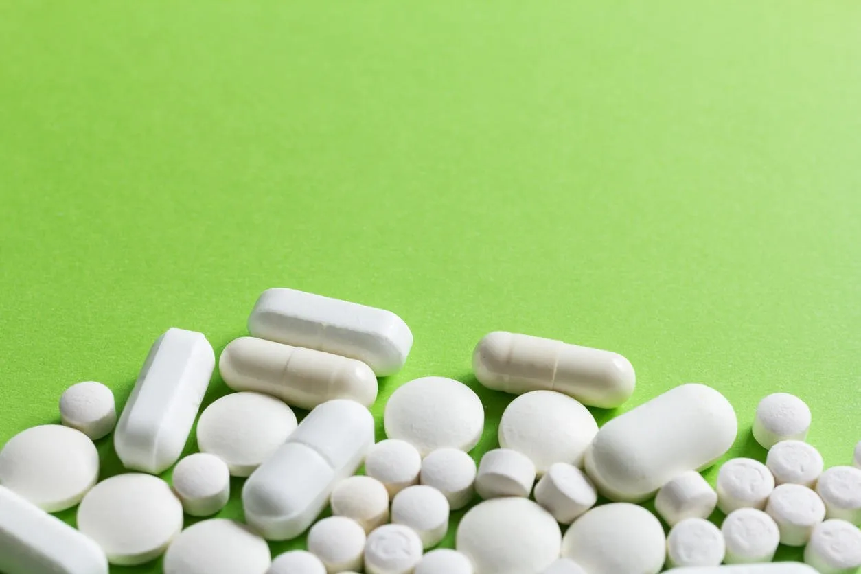 heap of white capsules on green table