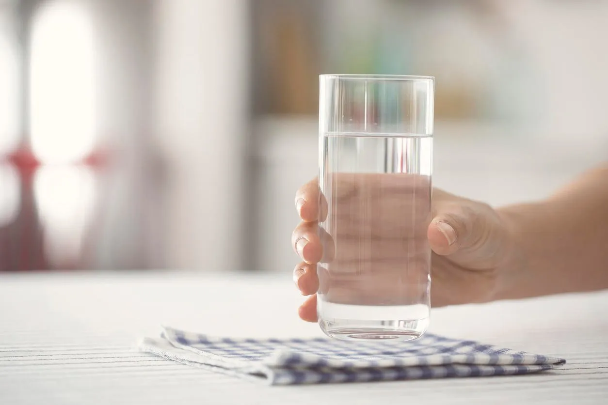 female holding glass of water on kicthen table