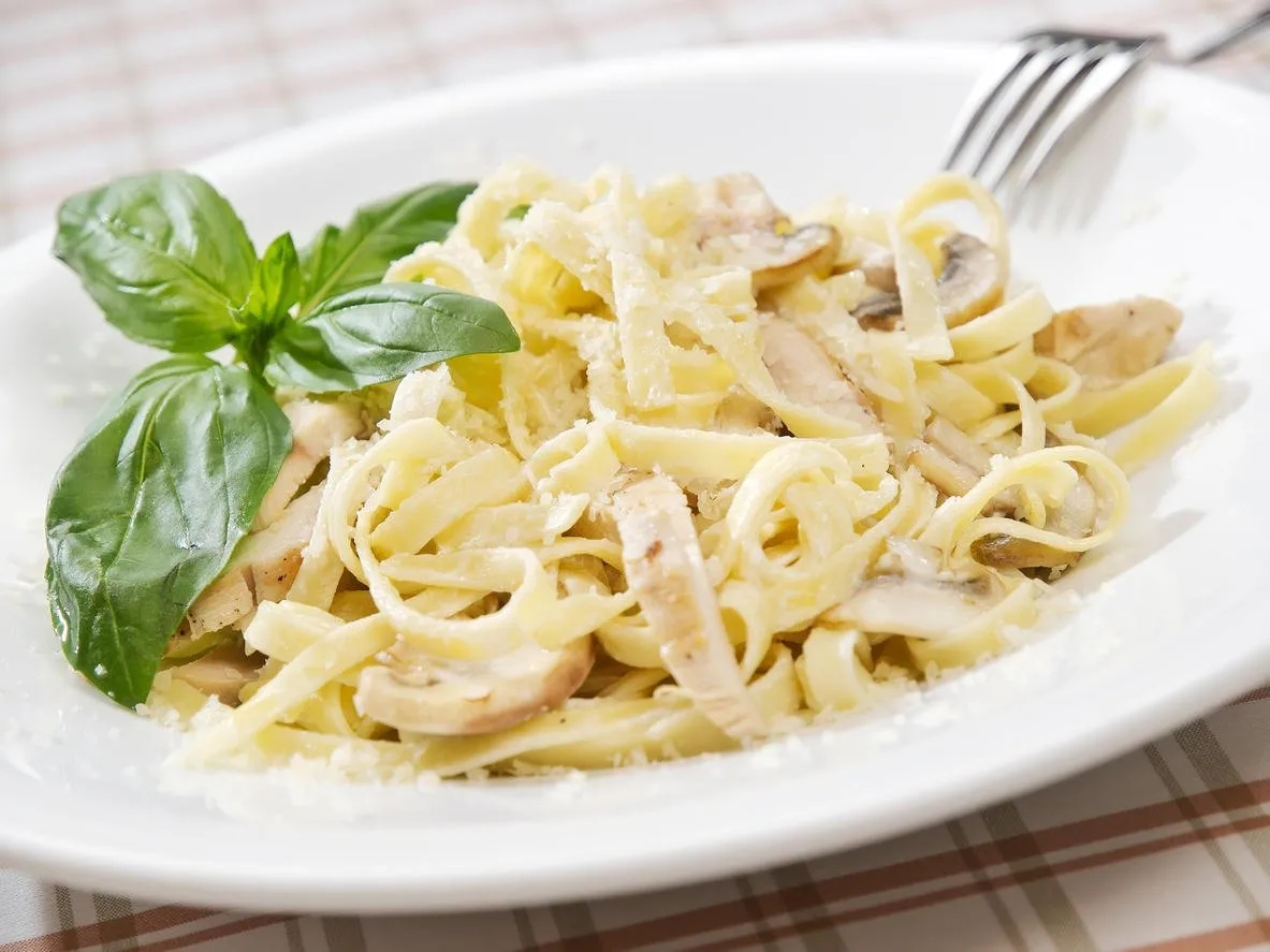 pâtes fettuccine alfredo au poulet, parmesan et persil sur fond de bois bleu bouchent cuisine italienne
