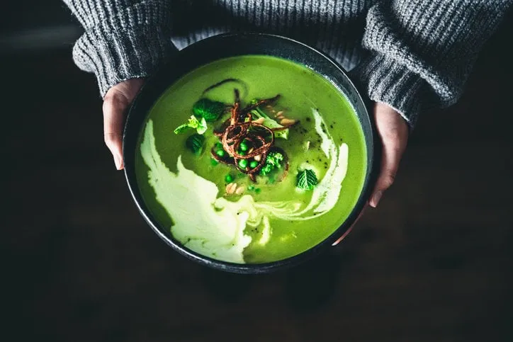 close-up shot of a woman holding a bowl of freshly made vegan soup female hand holding a plate of green soup