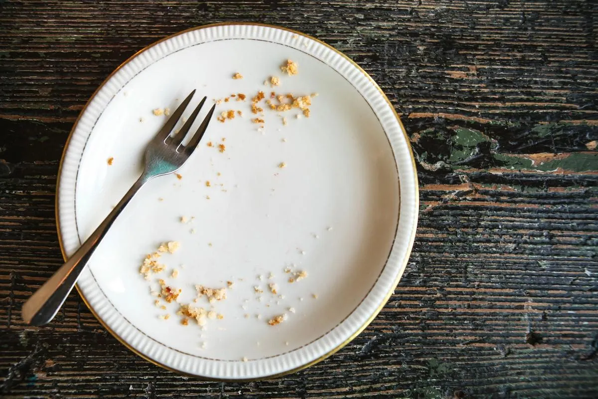 conceptual image of the end of the holiday is an empty plate with crumbs and a fork on it