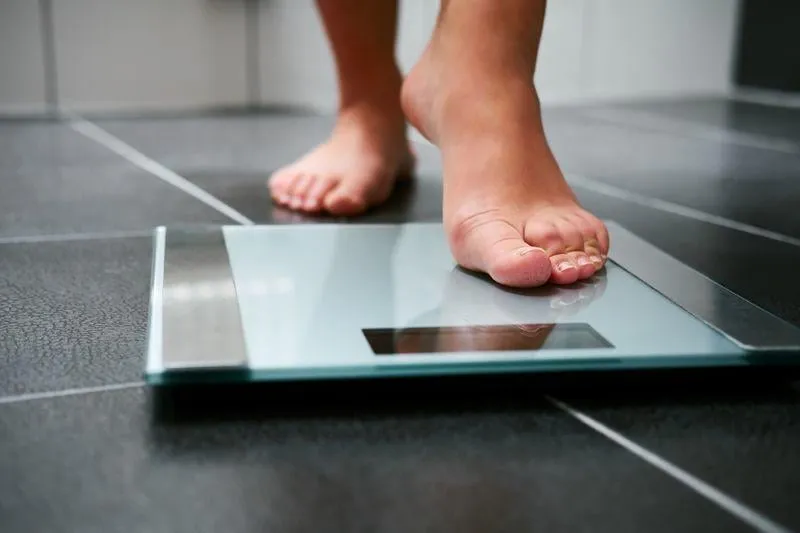 female bare feet with weight scale in the bathroom