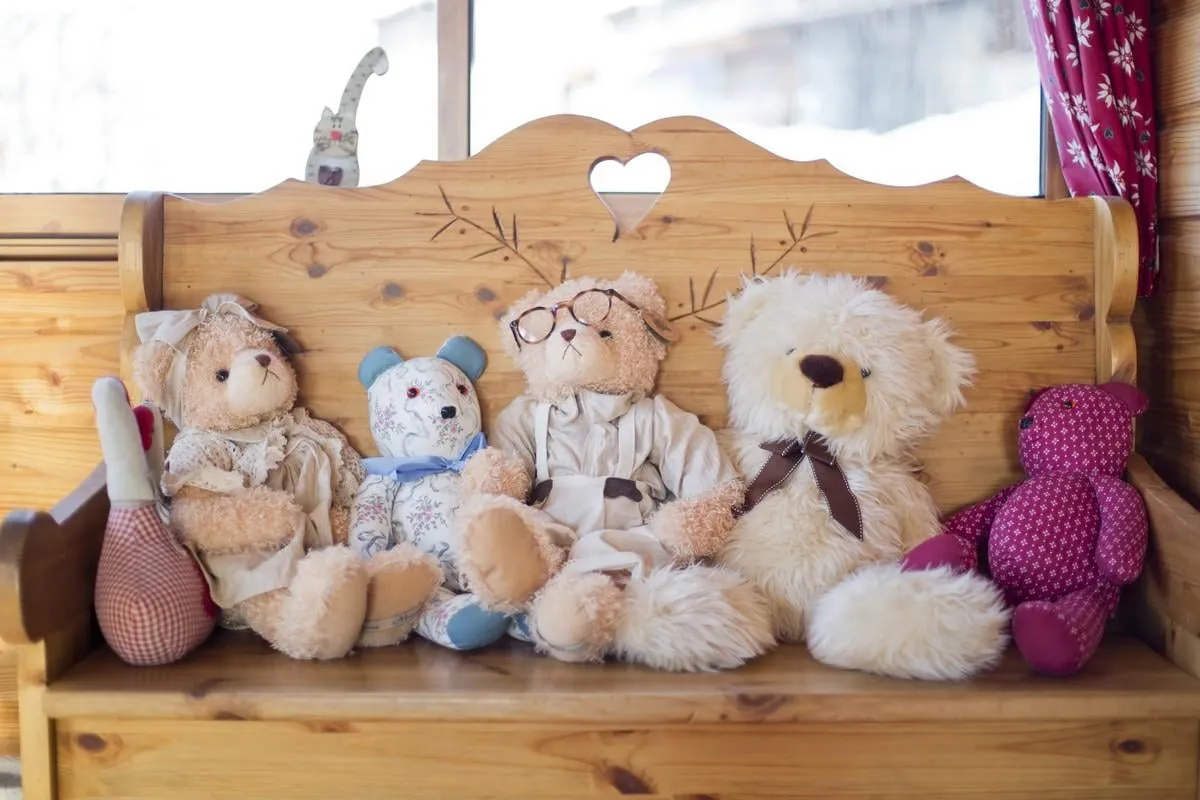 ours en tissu et en peluche assis sur un petit banc en bois