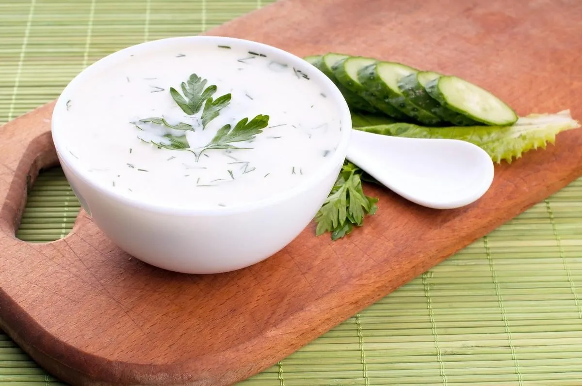 cold soup with avocado, cucumber and yogurt on a wooden board, top view