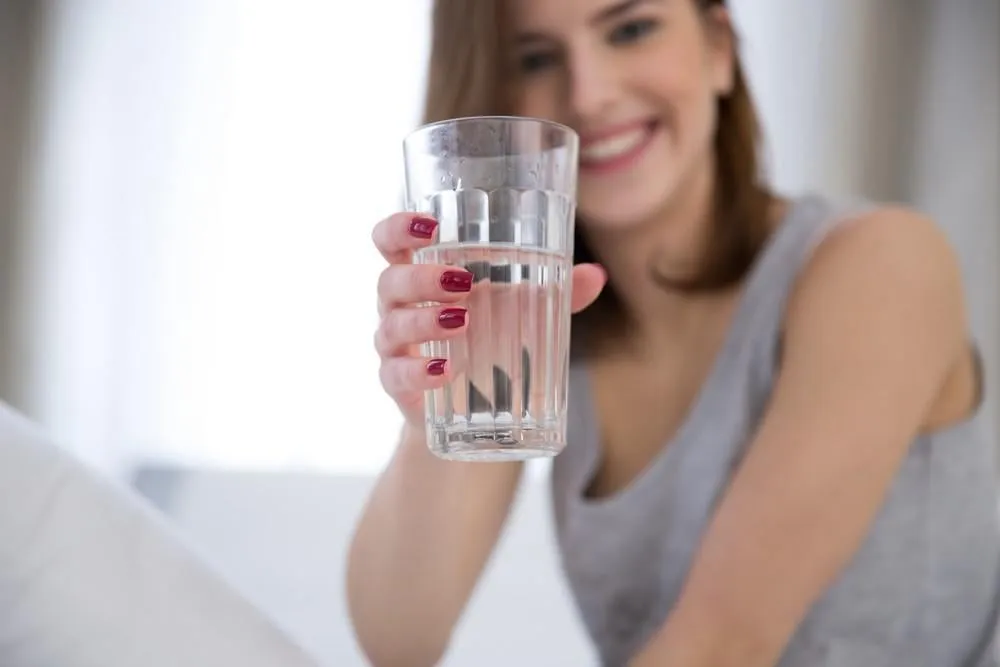 portrait d'une femme heureuse tenant le verre d'eau se concentrer sur le verre