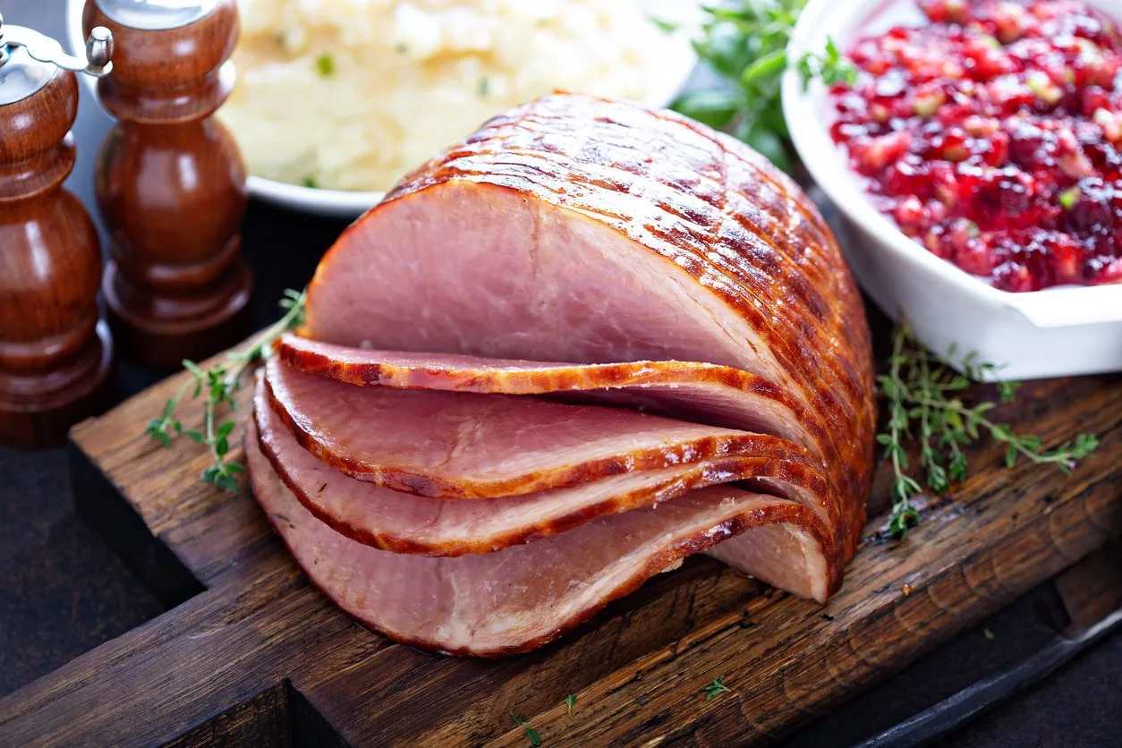 holiday glazed sliced ham on dinner table for thanksgiving or christmas