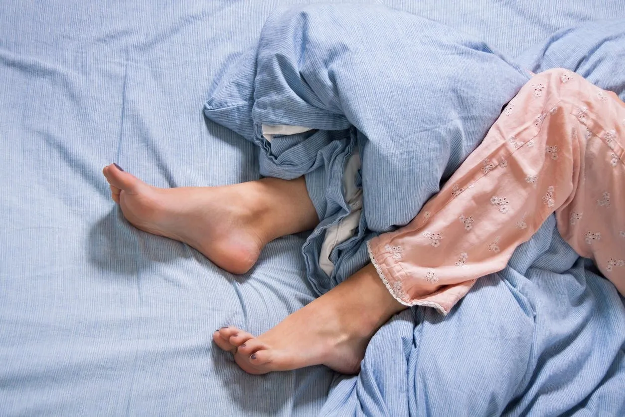 bouchent les pieds nus d'une jeune femme allongée sur un lit bleu, capturé en haute vue d'angle