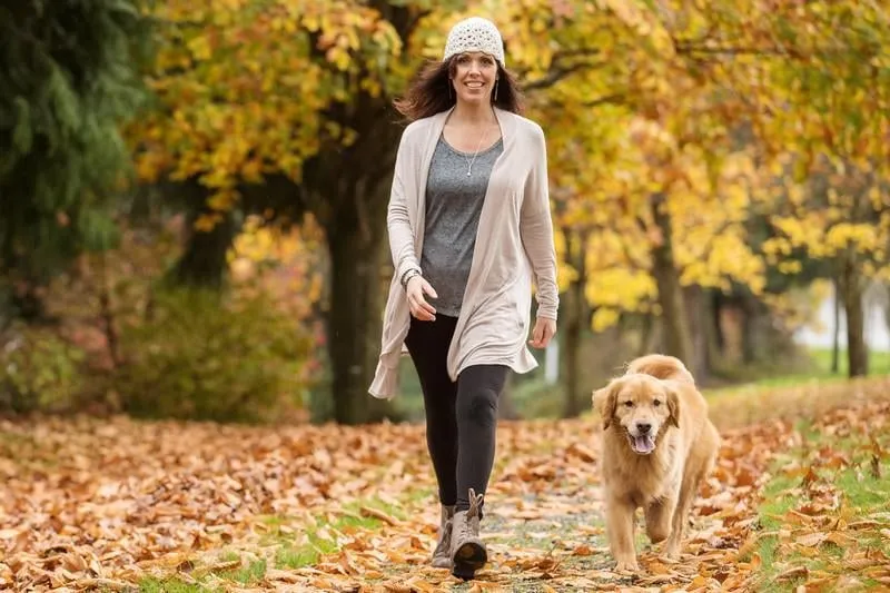 femme heureuse, promener son golden retriever chien dans un parc avec chute
