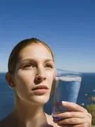femme tenant un verre d'eau contre sa joue