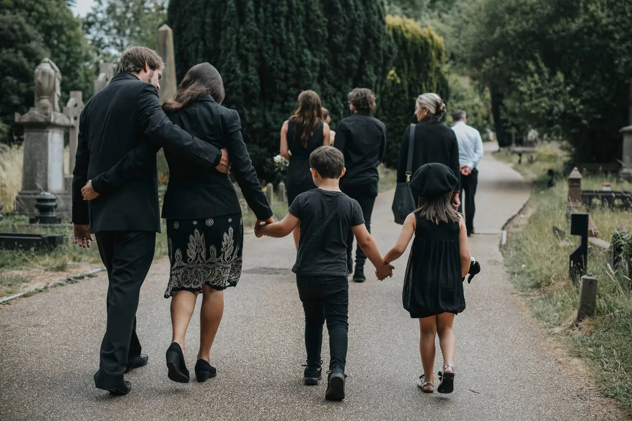 grieving family walking through a cemetery