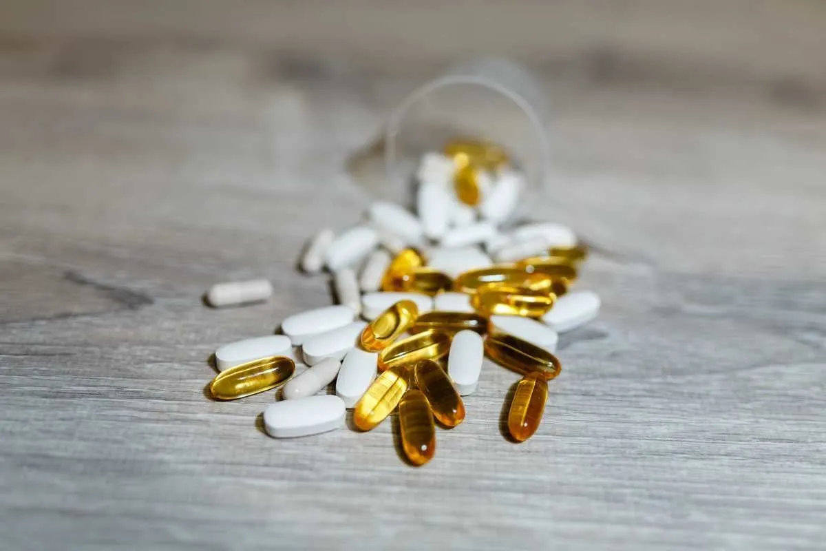 omega 3, carnitine, creatine, fat burner, bcaa and testosterone booster scoop for whey protein pills and capsules sports medical vitamins a scoop of protein on a gray wooden background