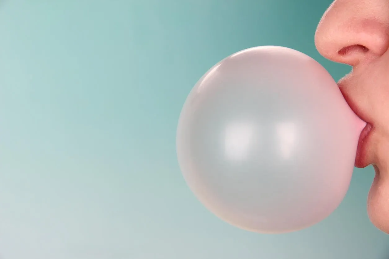person doing bubble with chewing gum on bright background