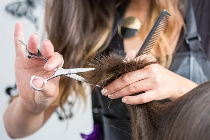 close up of a hairdressers hands cutting wet hair in a hair salon