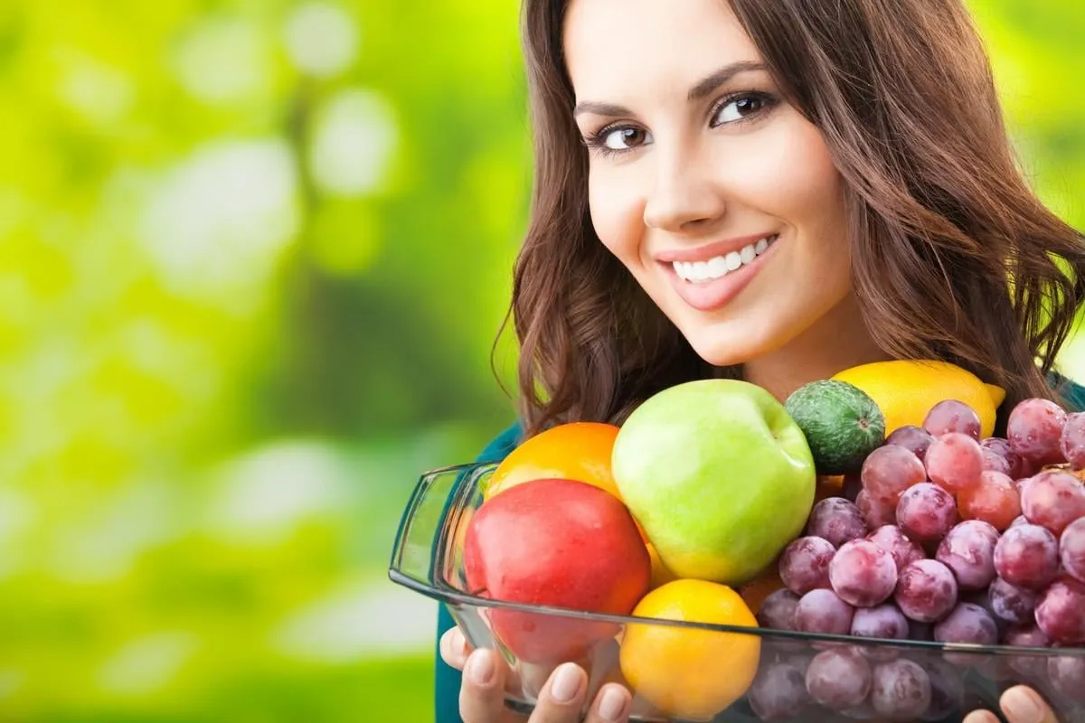 young happy smiling woman with plate of fruits, outdoors, with copyspace for text or slogan