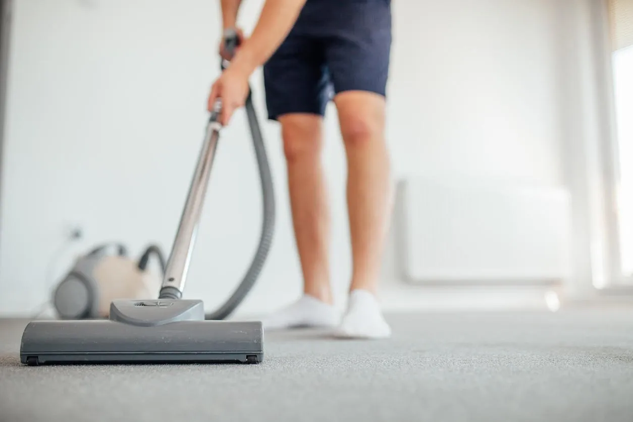 man is vacuuming home floor