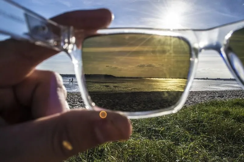 une photo dlsr du point de vue des personnes (pov) regardant à travers une paire de lunettes de soleil polarisées herbe couverte dune au premier plan avec le port de l'océan dans le fond pris à poole, dorset, uk
