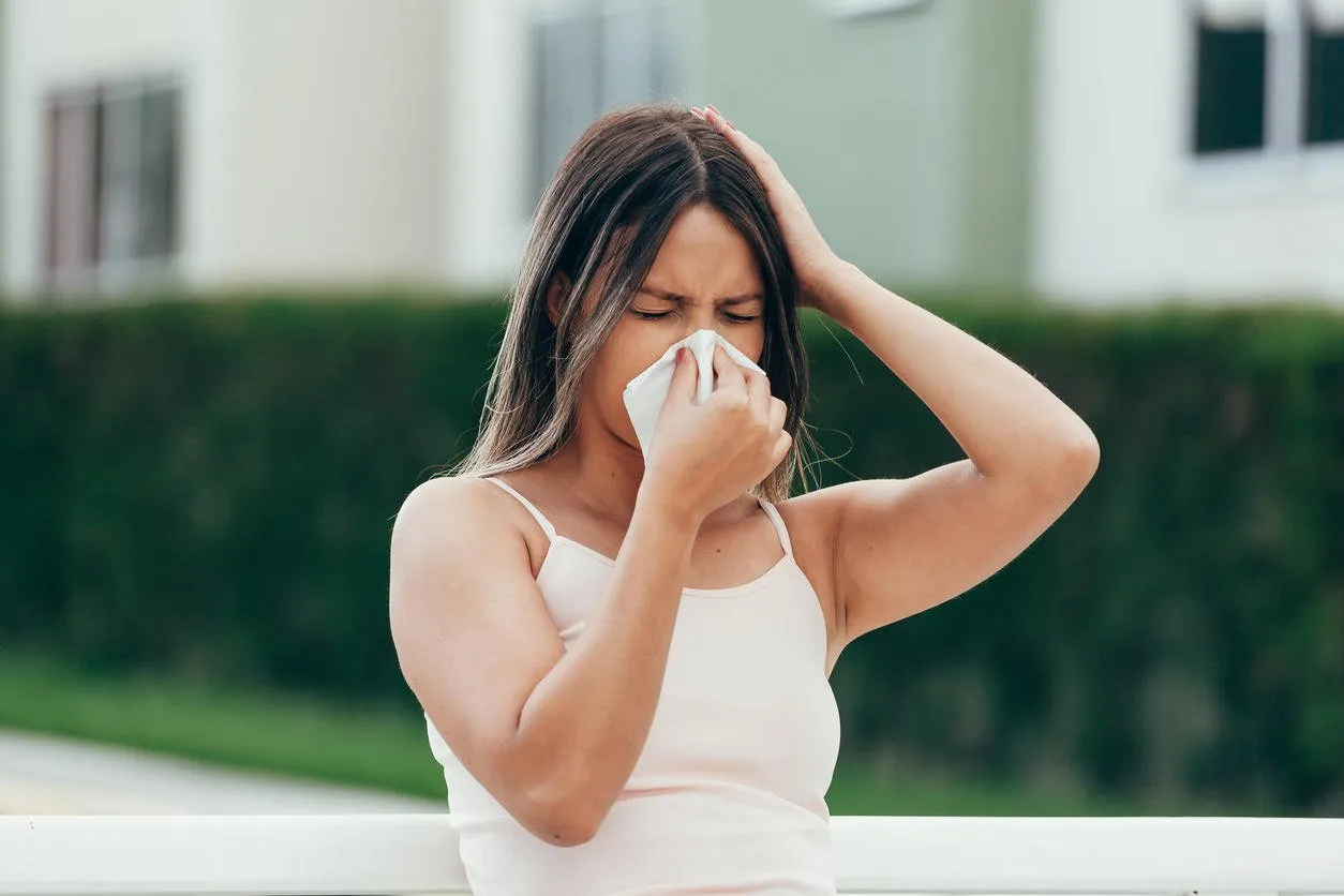 woman with allergy symptom blowing nose