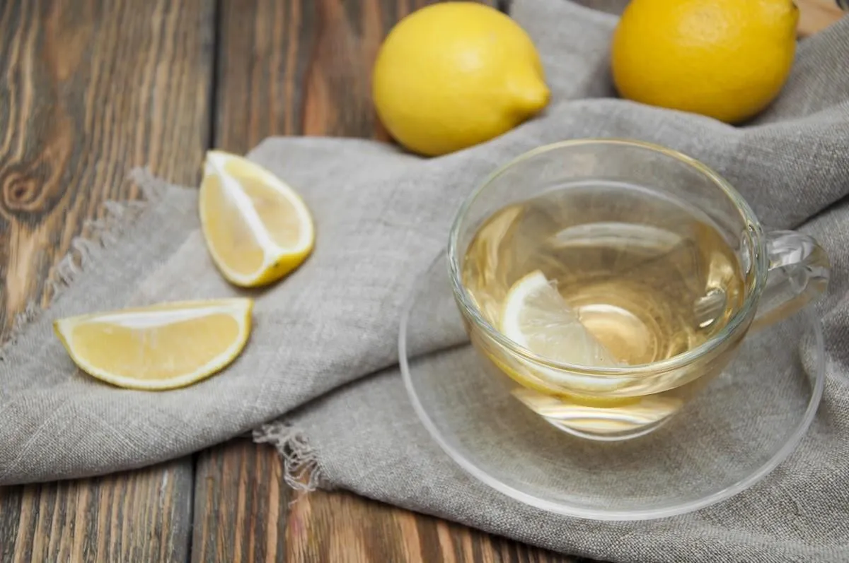 a cup of tea with lemon on a wooden background