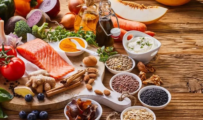 wide choice of healthy food ingredients surrounding salmon on cutting board and table