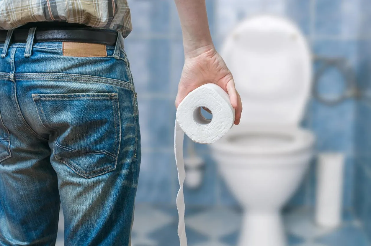 l'homme souffre de diarrhée tient rouleau de papier toilette devant la cuvette des toilettes