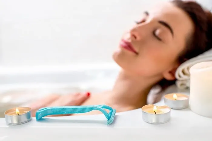 rasoir jetable sur le bain avec la femme couchée sur le fond