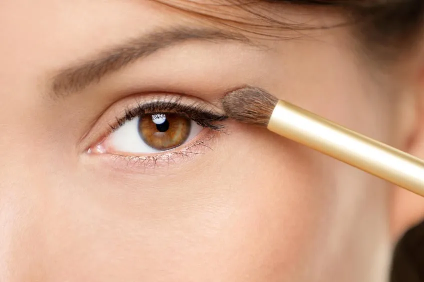 femme de maquillage pour les yeux en appliquant la poudre à paupières femme mettant la poudre d'ombre sur les yeux avec le pinceau de maquillage closeup de la paupière et des sourcils