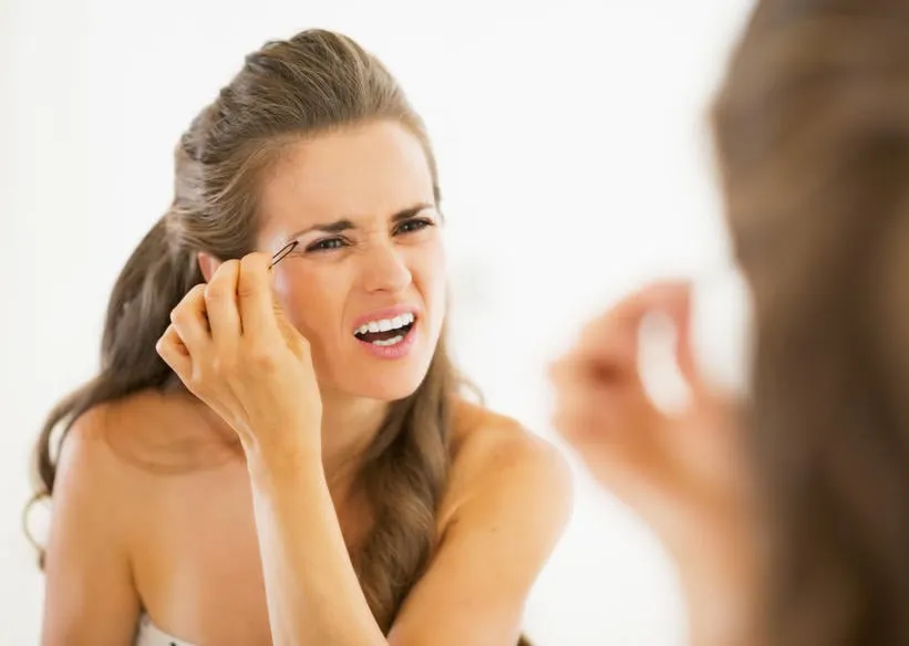déplaisante jeune femme tweezing sourcils