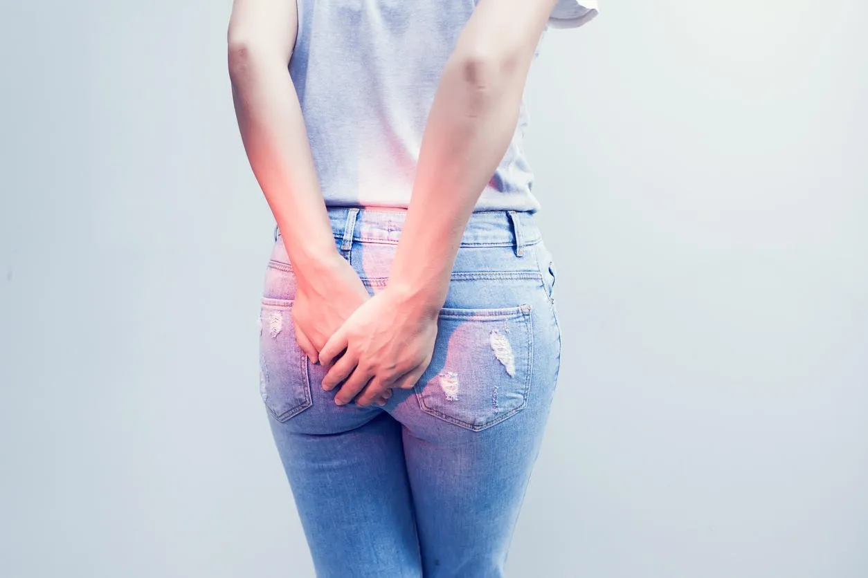 woman hand holding her bottom because having abdominal pain and hemorrhoids, health care concept